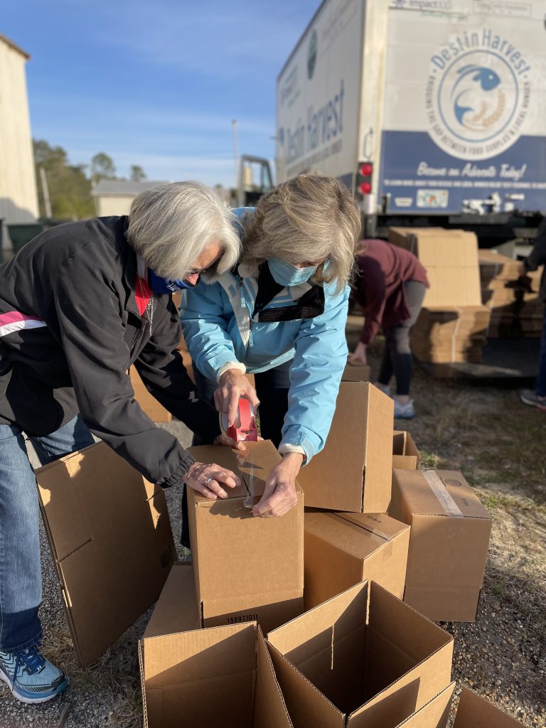 Two women preparing boxes at food distribution at NWFL Fairgrounds.