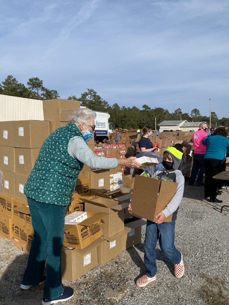 Volunteer helps young boy with preparing food box.